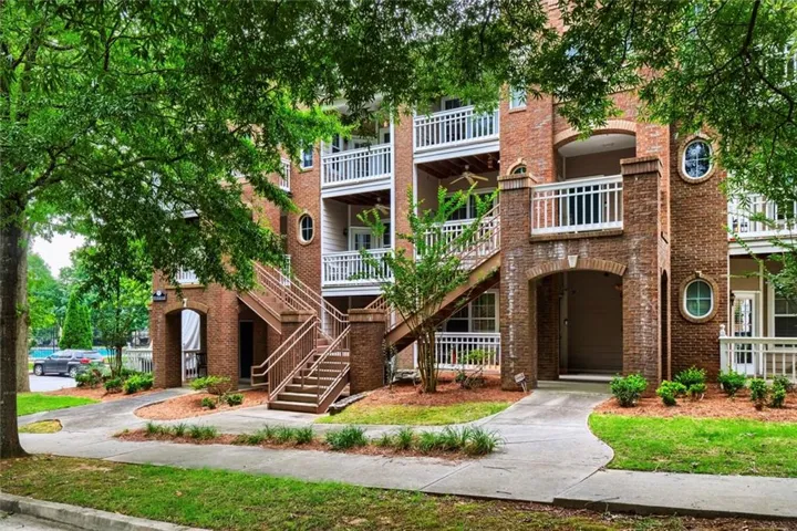 Multi-story brick building facade featuring multiple private balconies, arched entryways, and exterior staircases