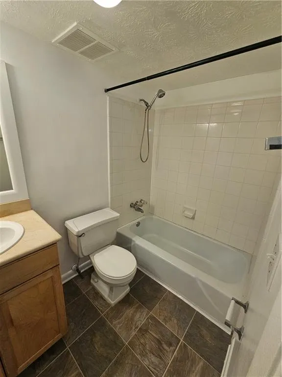 Full bath featuring a textured ceiling,  shower combination, and vanity