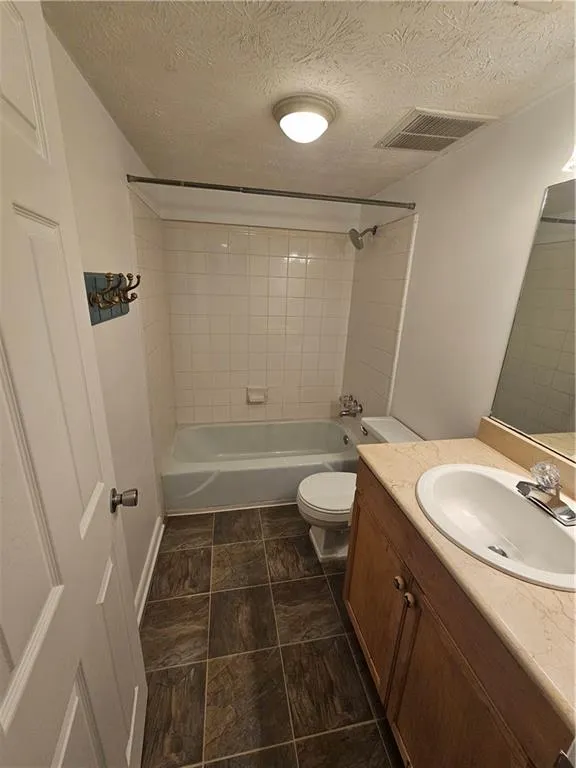 Bathroom featuring shower / tub combination, vanity, and a textured ceiling