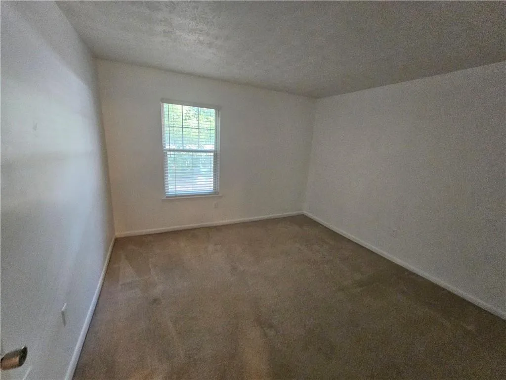 Carpeted 2nd bedroom featuring a textured ceiling and baseboards