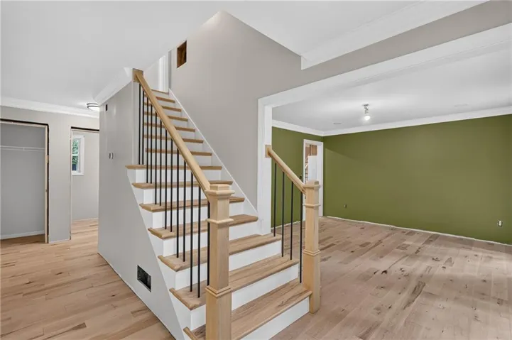 Hardwood flooring throughout the main level complements the staircase featuring natural wood handrails and black metal balusters