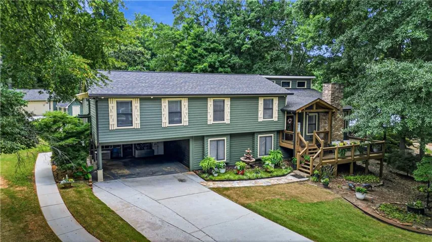 Multi-level home featuring a covered carport, expansive exterior deck, and a stone chimney