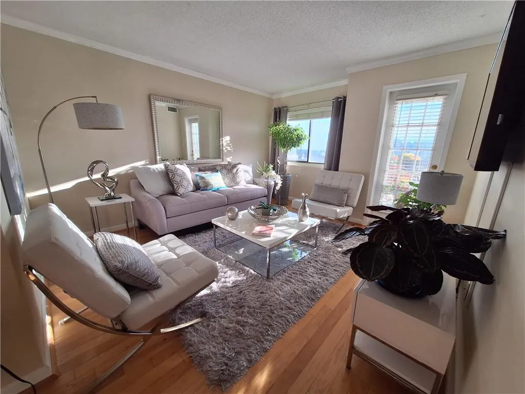 Living room with ornamental molding, wood finished floors, and a textured ceiling