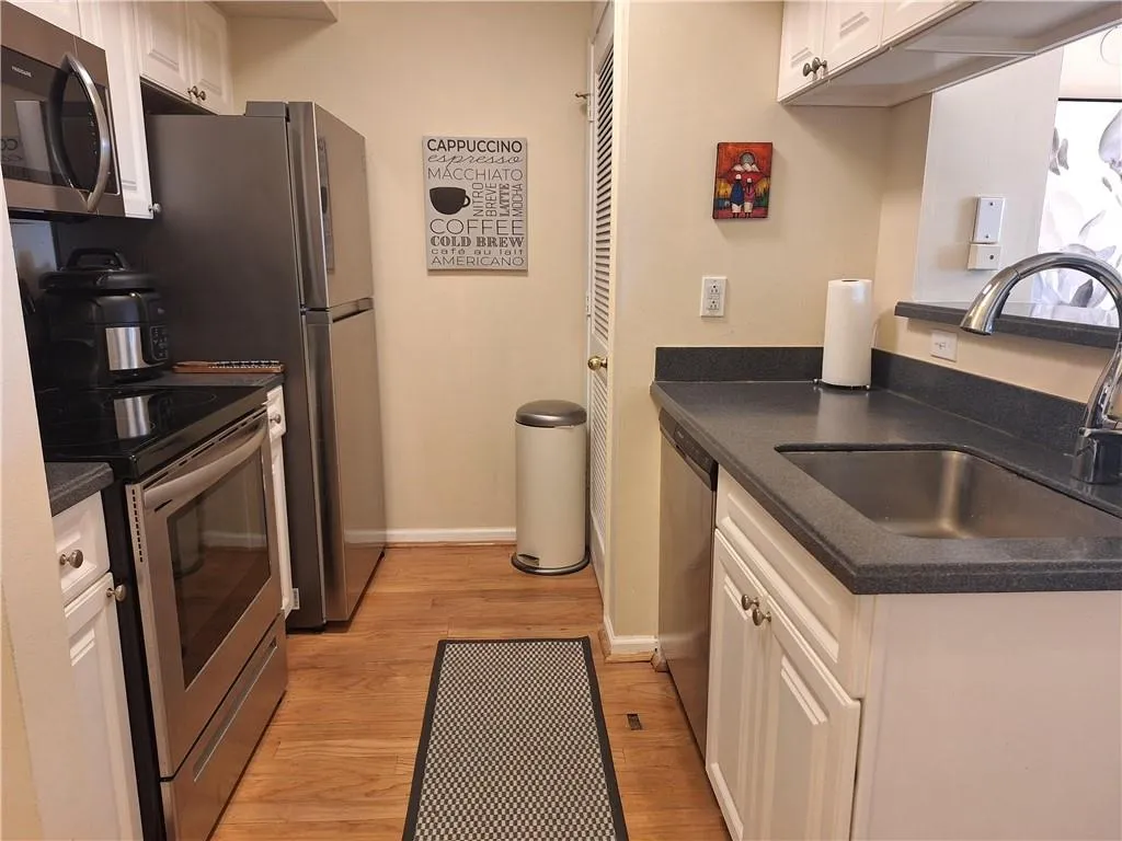 Kitchen with stainless steel appliances, white cabinets, and light wood-style floors