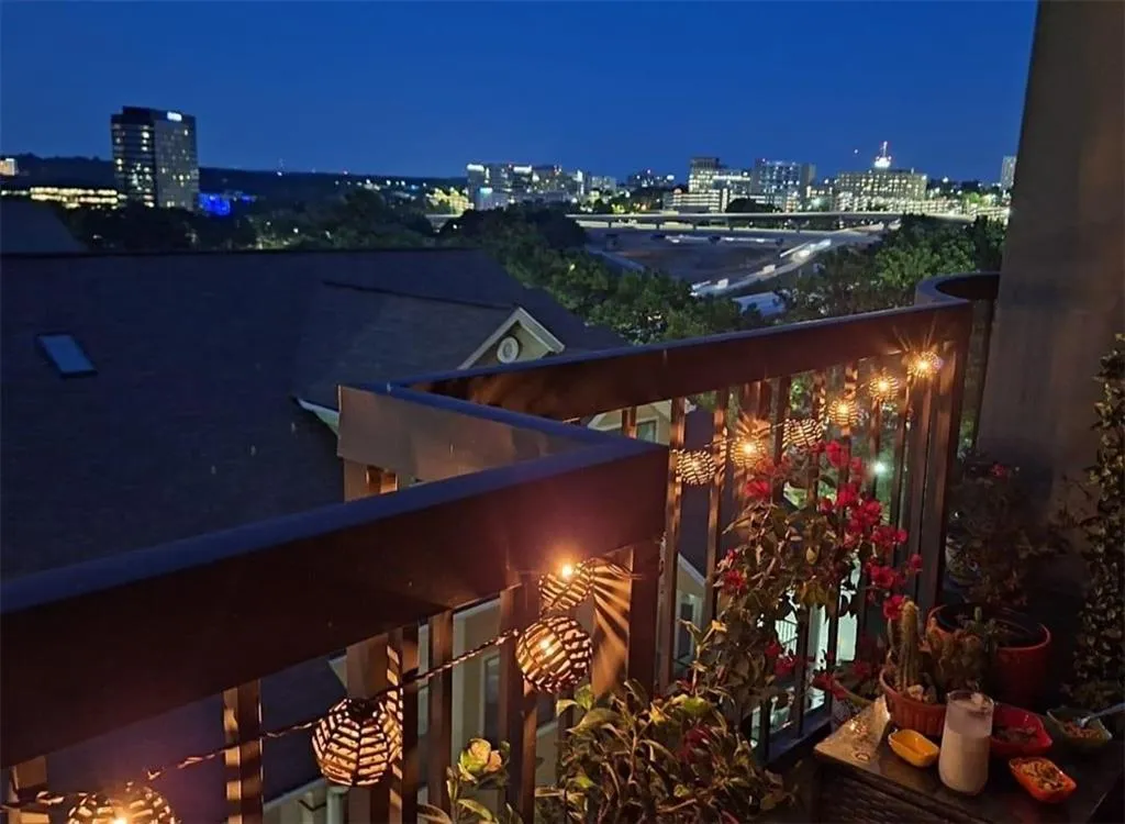 Balcony at night featuring a view of city lights