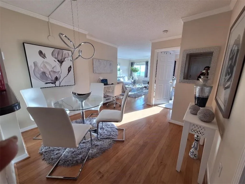 Dining area featuring a textured ceiling, wood finished floors, crown molding, and a chandelier