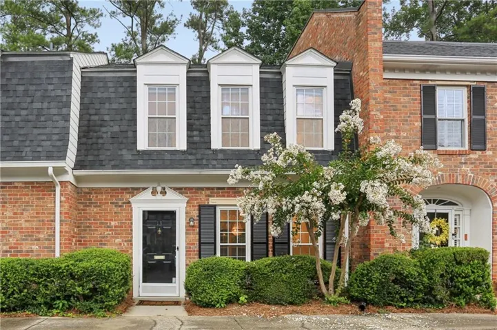 Brick exterior with a mansard roof, dormer windows, and black shutters