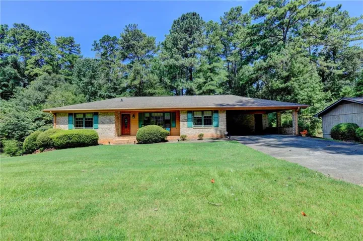 Brick exterior with a covered carport and a sloped front lawn