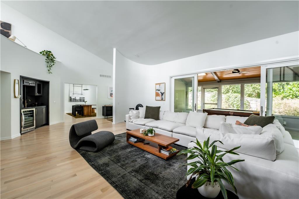 Living room with light hardwood / wood-style floors, high vaulted ceiling, and wine cooler