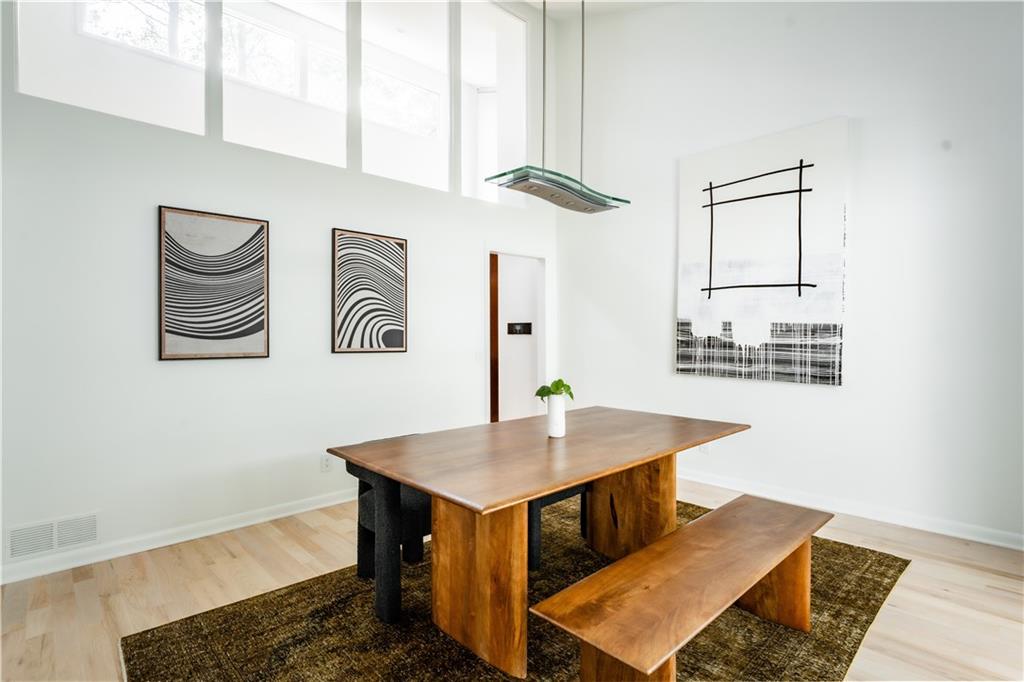 Dining space featuring light wood-type flooring, a towering ceiling, and a wealth of natural light
