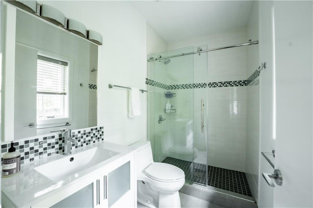 Bathroom with oversized vanity, toilet, backsplash, a shower with shower door, and tile flooring