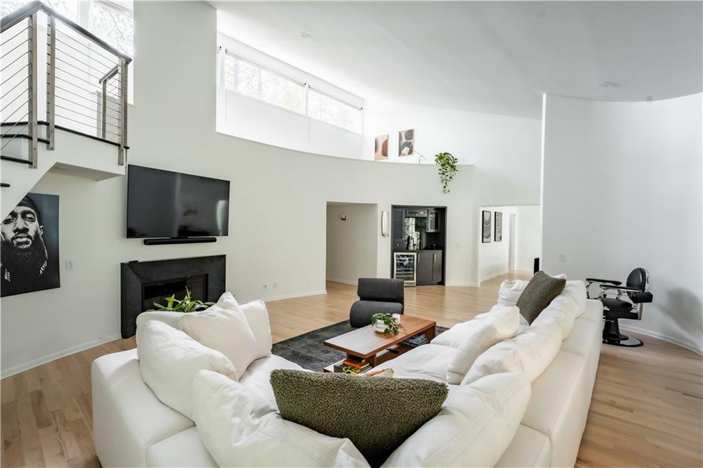 Living room with light hardwood / wood-style flooring, wine cooler, and a towering ceiling