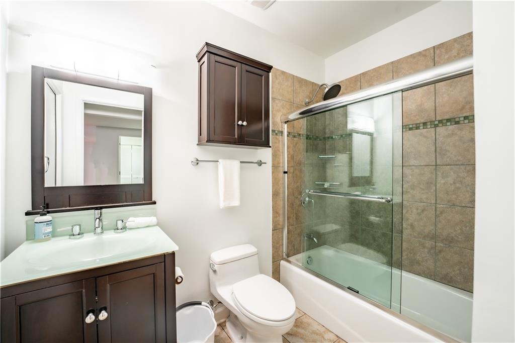 Full bathroom with tile floors, vanity, toilet, and combined bath / shower with glass door