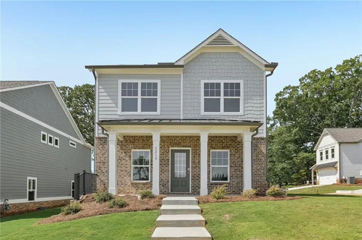 Two-story residence featuring brick and siding facade, front porch with columns, gabled roofline, and established landscaping