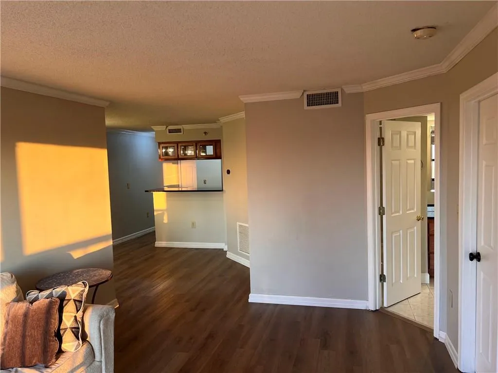 Unfurnished living room featuring crown molding, wood finished floors, and a textured ceiling