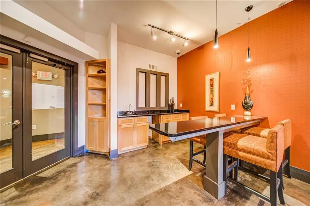 Kitchen with finished concrete flooring, dark countertops, decorative light fixtures, and rail lighting