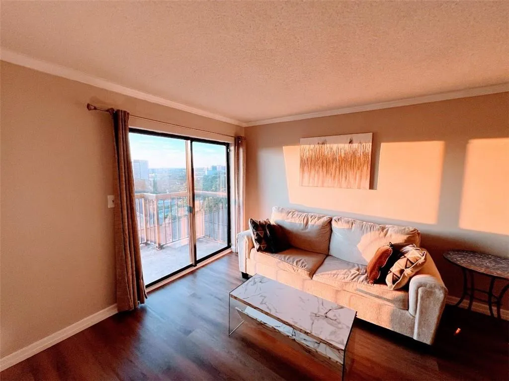 Living area featuring crown molding, wood finished floors, and a textured ceiling