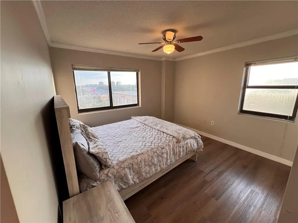 Bedroom featuring ornamental molding, dark wood-style floors, a textured ceiling, and a ceiling fan