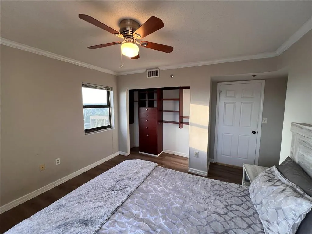 Bedroom with crown molding, dark wood-type flooring, a closet, and ceiling fan
