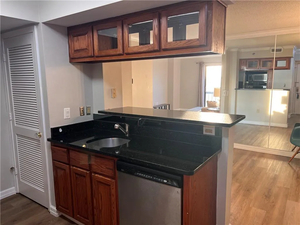 Kitchen with stainless steel appliances, ornamental molding, dark wood finished floors, dark countertops, and a peninsula