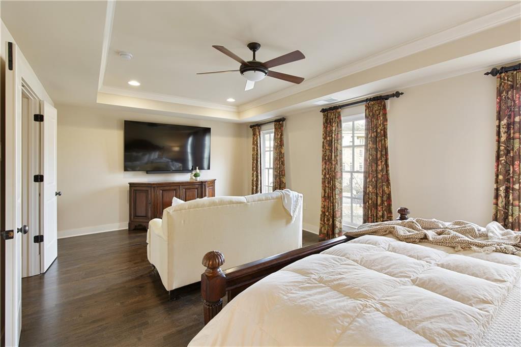 The luxurious primary suite, featuring a cozy sitting room perfect for relaxing evenings in, complemented by elegant custom drapes that add a touch of sophistication and privacy, creating a serene and personal retreat within the home.