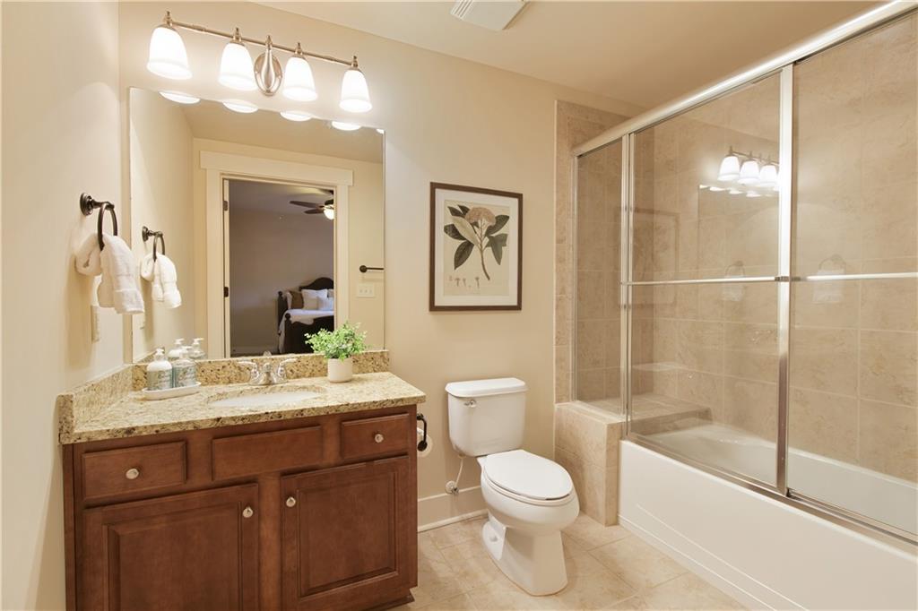 The stylish terrace level ensuite bathroom, equipped with sleek granite countertops and a practical tub-shower combo, merging luxury with functionality, and offering a polished and convenient bathing experience.