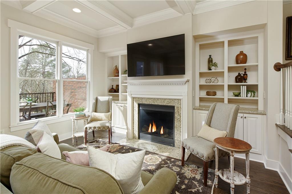 Capturing the charm of the living room, enhanced by a cozy fireplace, built-ins, and coffered ceilings, creating an inviting space for relaxation and entertainment.