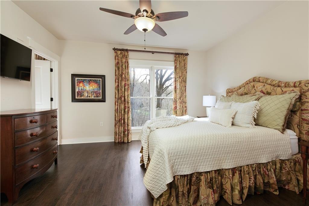 The secondary bedroom that includes an ensuite bath, elegant hardwood floors, walk-in closet, and a serene view of the surrounding woods and a gently babbling stream, creating a peaceful and restful retreat perfect for relaxation and rejuvenation.