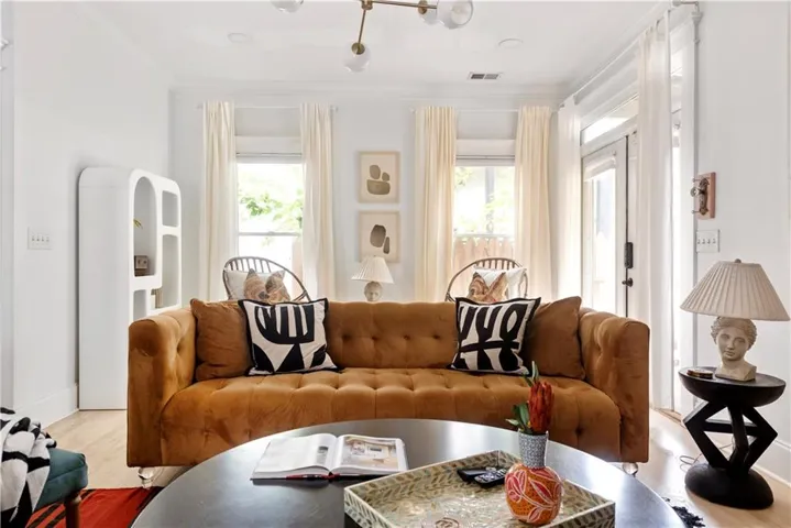 Living room with plenty of natural light, wood finished floors, and ornamental molding