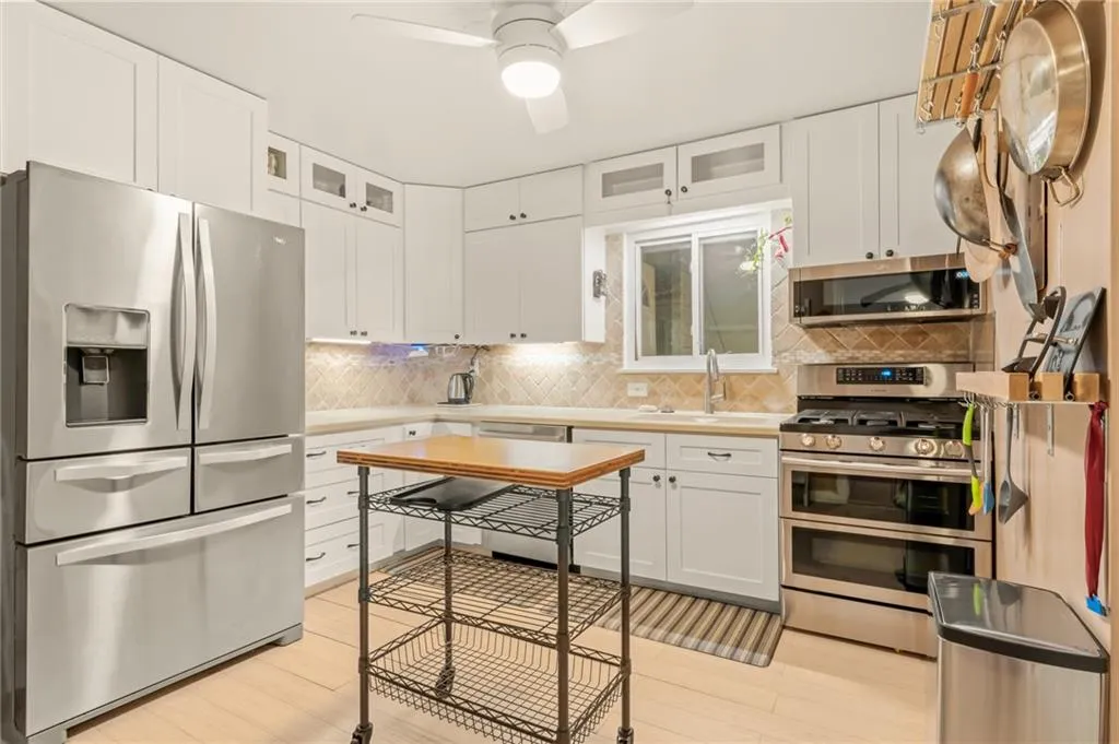 Bamboo inspired wood flooring in the kitchen accented by stainless appliances, stone counters and updated cabinetry.