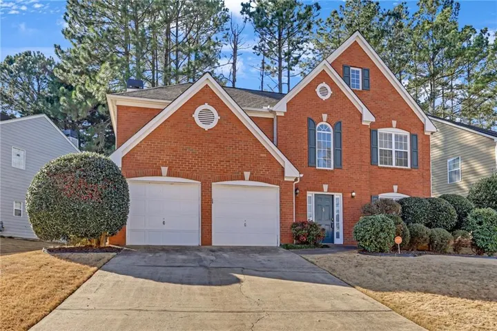 View of front of house featuring concrete driveway, brick siding, a garage, and a shingled roof