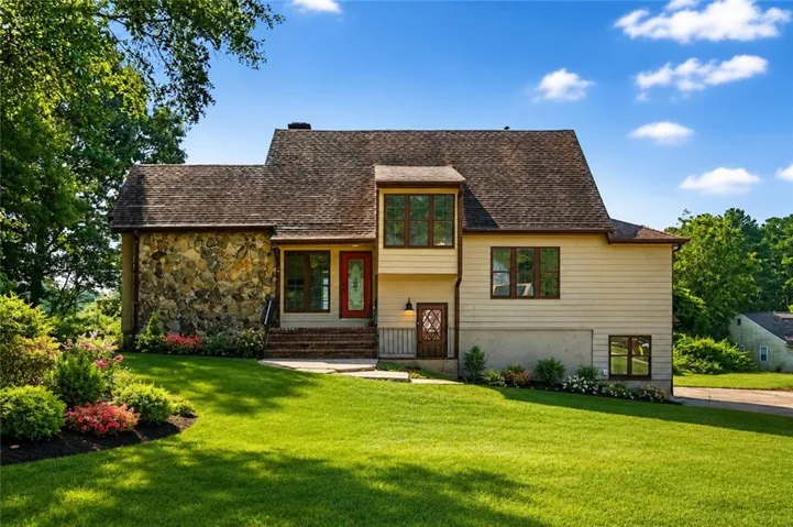 Stone facade and siding exterior with a shingle roof
