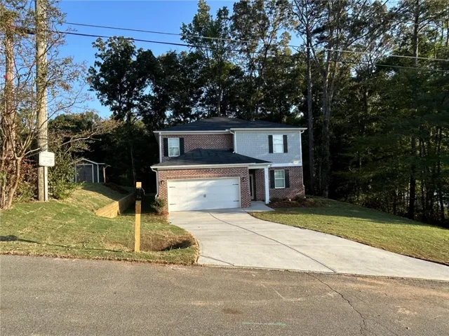 Two-story exterior with brick and siding facade, attached two-car garage, concrete driveway, and a backyard storage shed