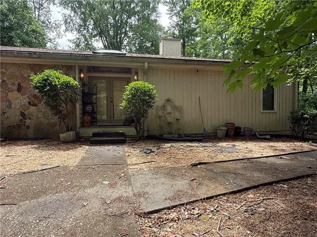 Mid-century modern exterior featuring a natural stone facade, double-door entry, a skylight, and a chimney