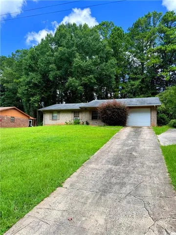 Brick ranch-style home featuring an attached garage with a white door, a paved driveway, and a broad front lawn