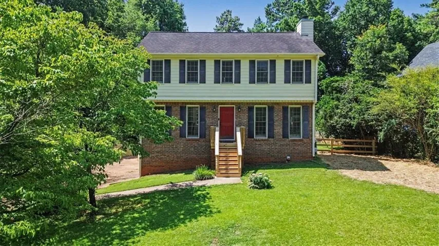 Traditional two-story residence featuring a brick facade on the lower level, light-colored siding on the upper level, and a dark shingle roof