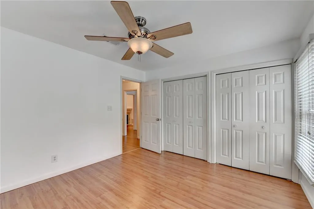 Unfurnished bedroom featuring multiple windows, light wood-style flooring, multiple closets, and baseboards