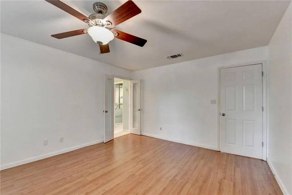Unfurnished room featuring visible vents, a ceiling fan, light wood finished floors, and baseboards