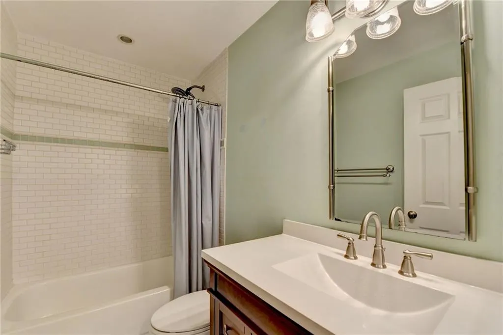 Bathroom with shower / tub combo with curtain, toilet, and vanity