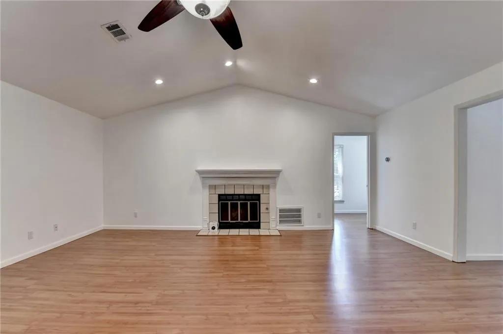 Unfurnished living room featuring visible vents, light wood-type flooring, recessed lighting, vaulted ceiling, and a ceiling fan