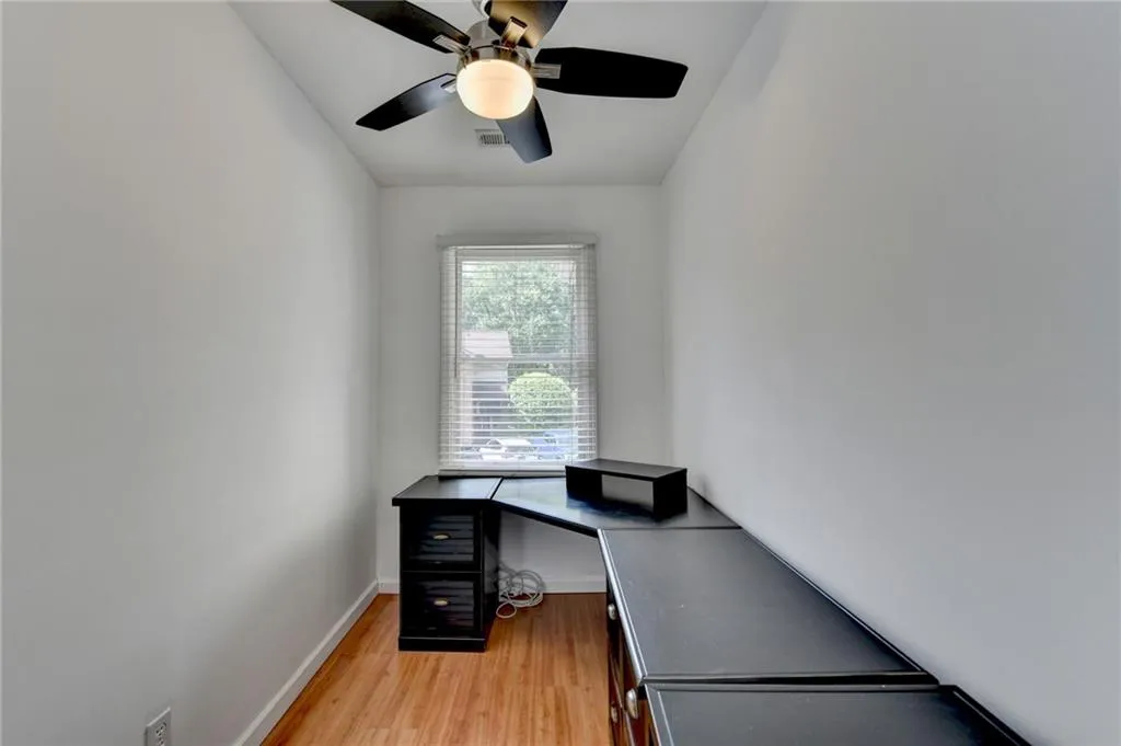 Home office featuring baseboards, light wood-type flooring, and ceiling fan