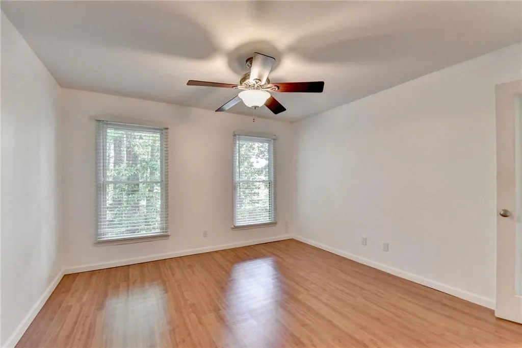 Spare room with baseboards, light wood-type flooring, and a ceiling fan