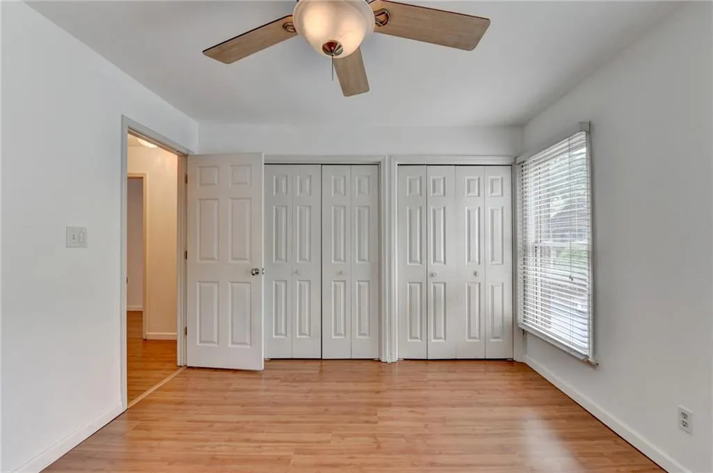 Unfurnished bedroom featuring light wood-style flooring, multiple closets, and baseboards
