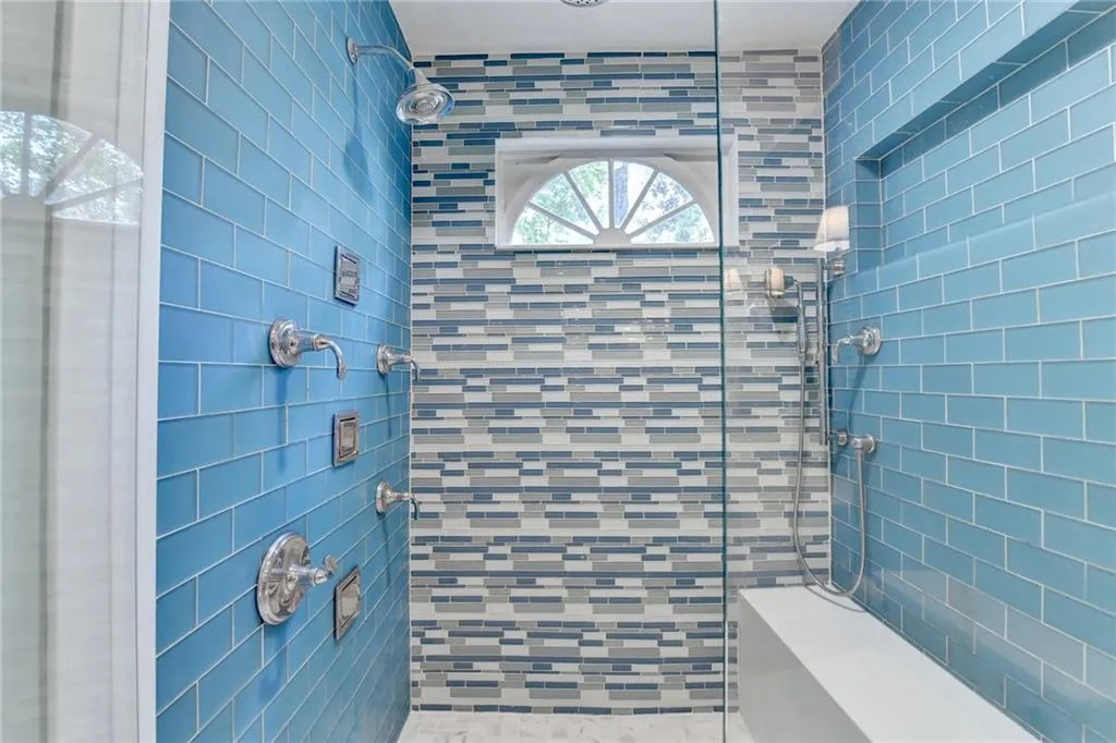 Full bathroom featuring a tile shower and tile walls
