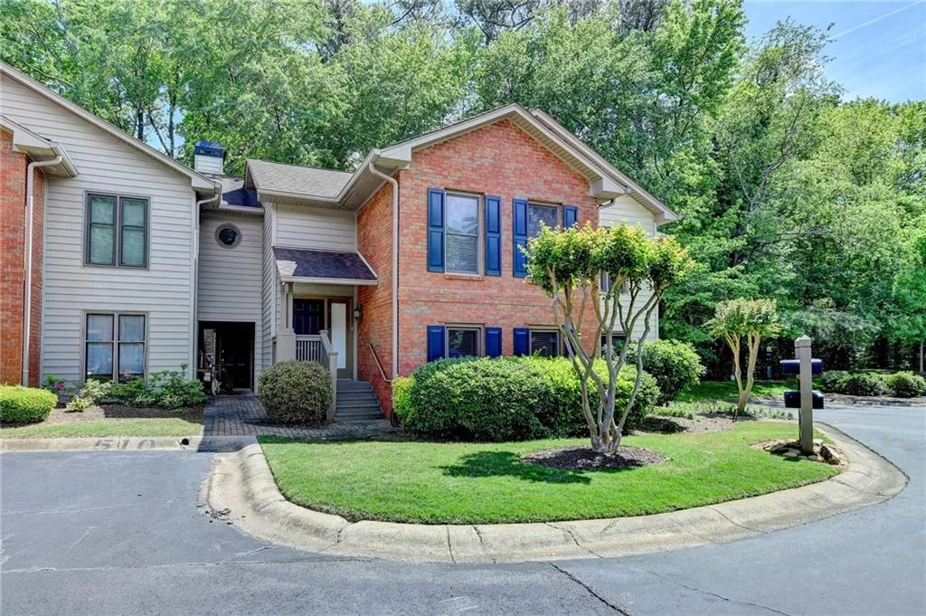View of front facade with a chimney, brick siding, a shingled roof, and a front yard