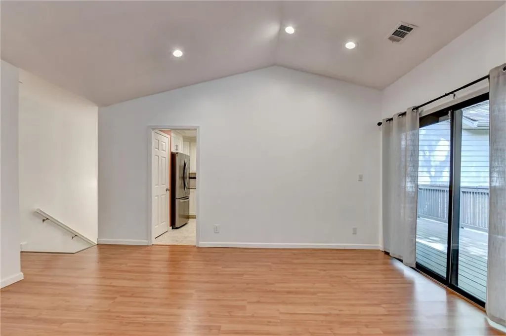 Empty room featuring visible vents, recessed lighting, light wood-style floors, and vaulted ceiling