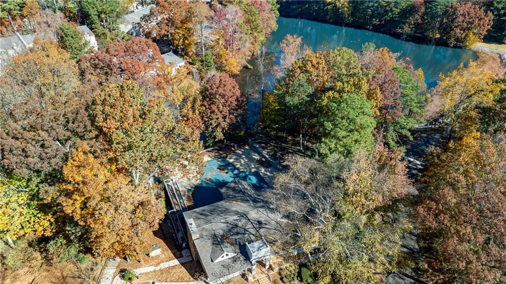 Drone / aerial view of a nearby body of water and a heavily wooded area