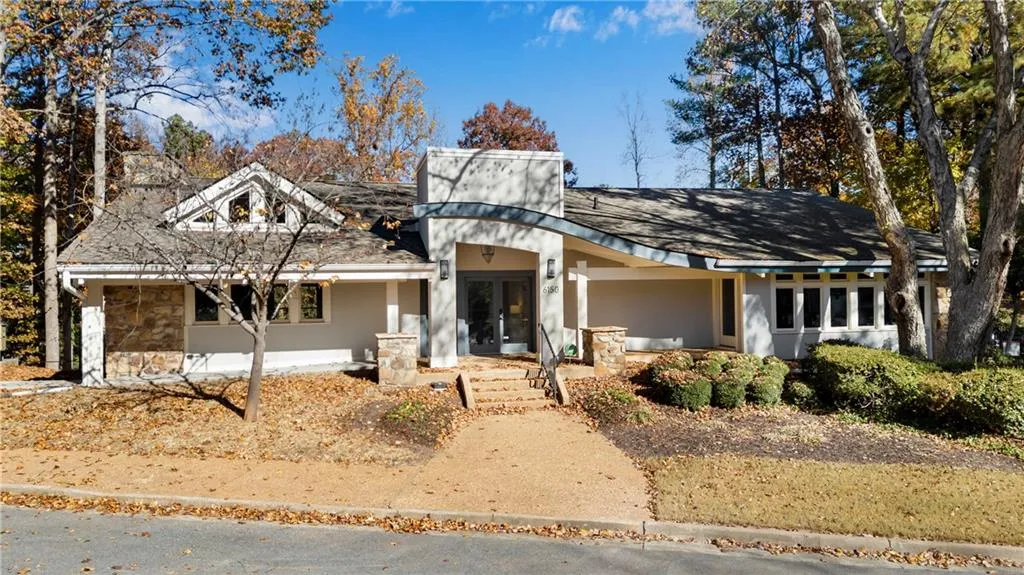 View of front of house with stone siding, stucco siding, and covered porch