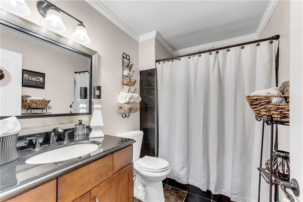 Bathroom with crown molding, vanity, a shower with curtain, and dark tile patterned floors