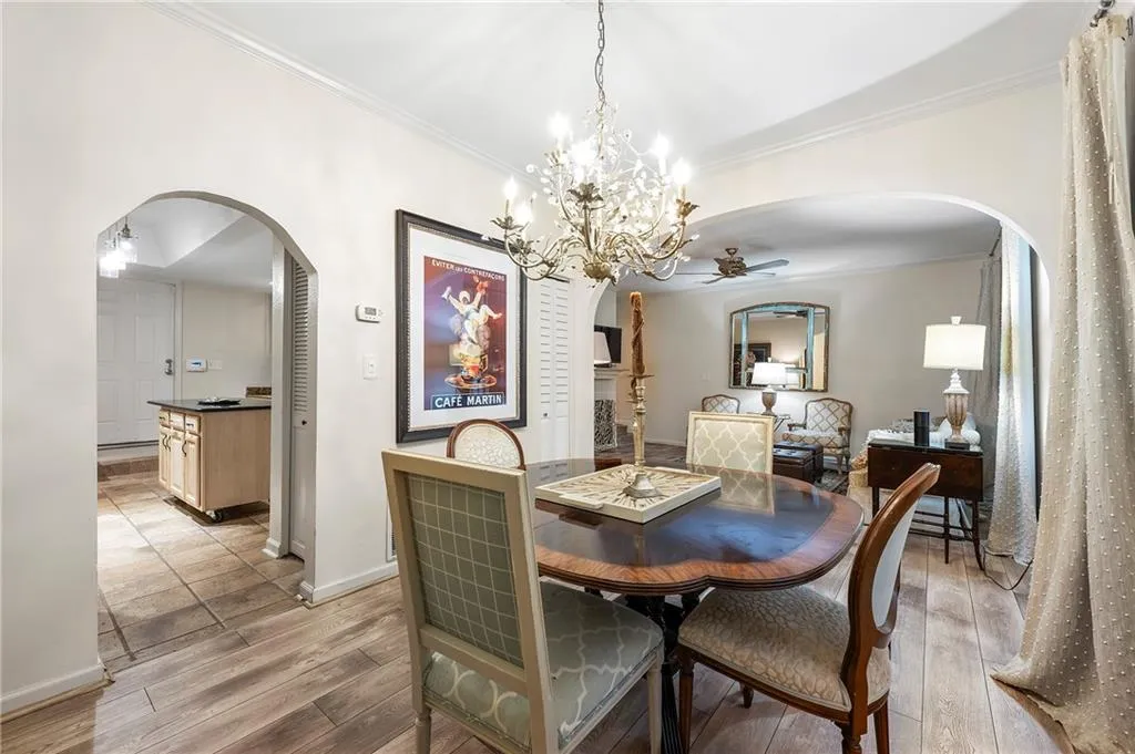 Dining space featuring ceiling fan with notable chandelier, light wood-type flooring, and ornamental molding